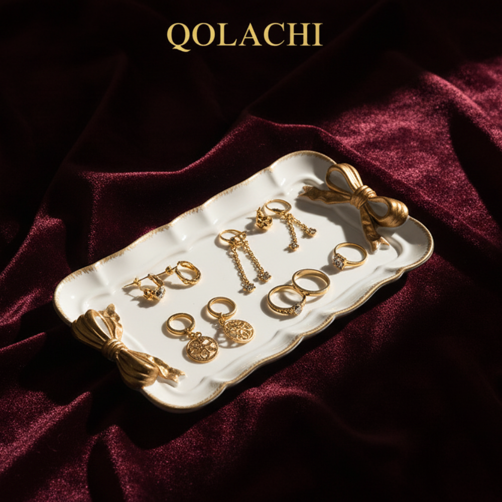 Qolachi white bow jewelry tray under golden spotlight on burgundy velvet background